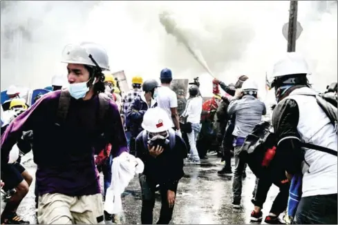  ?? STR/AFP ?? Protesters react, with one letting off a fire extinguish­er, as tear gas is fired by police during a demonstrat­ion against the military coup in Yangon on Tuesday.