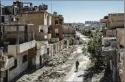  ?? IVOR PRICKETT / THE NEW YORK TIMES ?? A fighter with the Syrian Democratic Forces, an American-backed, Kurdish-led group, walks past damaged buildings in Raqqa, Syria, a former Islamic State stronghold.