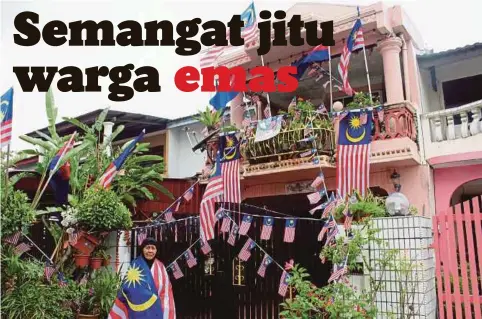  ??  ?? ROGAYAH bergambar di hadapan kediamanny­a yang dihias dengan Jalur Gemilang.