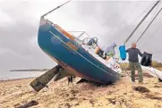  ?? PETER PEREIRA/STANDARD TIMES ?? Peter Raymond gets some help from Robert Freeman in retrieving items from his sailboat Ama on Monday after unexpected overnight high winds in Dartmouth, Mass.