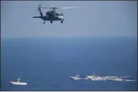  ?? The Associated Press ?? PATROL: In this Dec. 21, 2018, file photo, a U.S. MH-60 Seahawk helicopter flies over Iranian Revolution­ary Guard patrol boats in the Strait of Hormuz. The top U.S. Navy official in the Mideast, said Sunday, that America has reached an “uneasy deterrence” with Iran after months of regional attacks and seizures at sea, even as tensions remain high between Washington and Tehran over the Islamic Republic’s nuclear program.