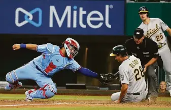  ?? Tony Gutierrez / Associated Press ?? Texas catcher Jose Trevino tries to tag A’s first baseman Matt Olson, who slides home safely after Sean Murphy’s eighth-inning double in Arlington. Olson had walked to reach base.