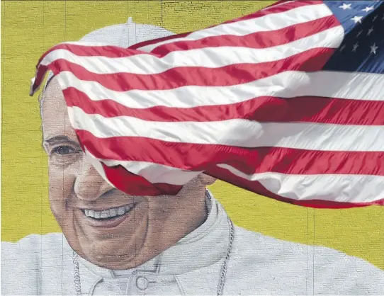  ?? TIMOTHY A. CLARY/AFP/GETTY IMAGES ?? A U.S. flag blows in front of a mural of Pope Francis across the street from Madison Square Garden in New York as the city prepares for his visit.