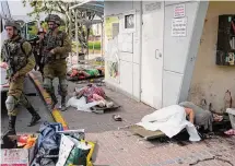  ?? Ohad Zwigenberg/Associated Press ?? Israeli soldiers walk through an area where civilians were killed by Palestinia­n militants Saturday in Sderot, Israel.