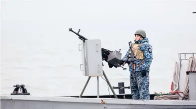  ?? ALEKSEY FILIPPOV/GETTY-AFP ?? A serviceman stands guard on a boat in the Black Sea port of Mariupol weeks before Russia’s invasion of Ukraine.