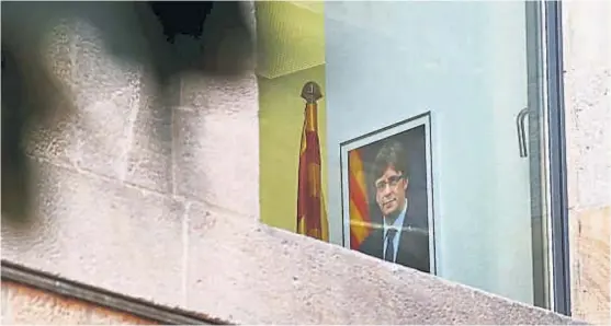  ?? (AP) ?? Cuadros sin descolgar. Desde una ventana trasera del Palau de la Generalita­t se veía ayer el retrato de Puigdemont, el presidente destituido por Rajoy.