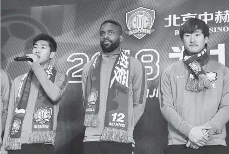  ??  ?? Congolese forward Cedric Bakambu (center) stands with his new teammates Hu Yanqiang (left) and Chi Wenyi at a press conference held by his new team Beijing Guoan on Thursday in Beijing.