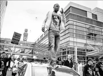  ?? Jim Watson/Getty Images ?? A demonstrat­or walks atop a Baltimore City police car Saturday as he and others march down S. Eutaw Street near Oriole Park at Camden Yards to protest the death of Freddie Gray, a black man who died of spinal cord injuries while in police custody.