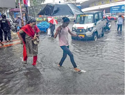  ?? PTI ?? Pedestrian­s hold umbrellas while trying to make their way across a street during a rain in Kochi on Monday. —