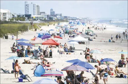  ?? Matt Born / Associated Press ?? Beachgoers hang out just north of Kure Beach Pier at Kure Beach, N. C., Saturday. The town lifted the majority of beach restrictio­ns related to the coronaviru­s on May 15.