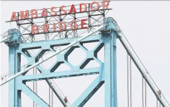  ?? DAN JANISSE ?? Workers are shown near the top of the Ambassador Bridge, near the Windsor shoreline on Monday. A local musician was charged after he climbed to the top of the bridge on the weekend in a publicity stunt.
