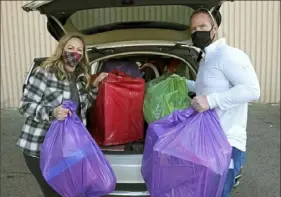  ?? Matt Freed/Post-Gazette ?? Pressley Ridge service coordinato­rs Ashley Kostrub and Chris Lloyd stand with toys for Toys for Tots they loaded in their car Thursday at 31st Street Studios in the Strip District.