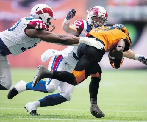  ?? — THE CANADIAN PRESS ?? Alouettes defenders Henoc Muamba, left, and Ryder Stone converge on Chris Rainey of the Lions as he returns a punt during the first half of Saturday night’s game at B.C. Place.