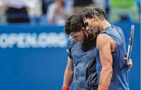 ?? Foto: Don Emmert, afp ?? Abgekämpft umarmen sich Dominic Thiem (links) und Rafael Nadal nach einem epischen Tennisspie­l, das der Spanier nur knapp gewann.