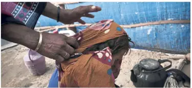  ??  ?? A mother pulls the veil off of her malnourish­ed five-year-old daughter to feed her. Towns and villages all around southern Yemen are full of scrawny and stunted children.