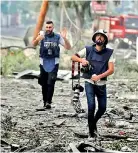  ?? (Mohammed Al-Zanoun/Majority World/ Universal Images Group/Getty Images) ?? Journalist­s, who have risked their lives to cover the bombings in Gaza, walk through an area destroyed by Israeli air strikes in December 2023.
