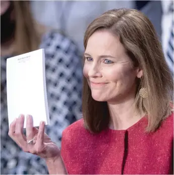  ?? BRENDAN SMIALOWSI/POOL VIA AP ?? Supreme Court nominee Amy Coney Barrett holds up a blank notepad Tuesday during her confirmati­on hearing before the Senate Judiciary Committee.