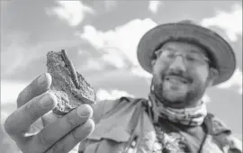  ??  ?? TYLOR BIRTHISEL, a paleontolo­gist and fossil prep lab manager, shows off a serrated tooth from a tyrannosau­r being unearthed on the Kaiparowit­s Plateau.