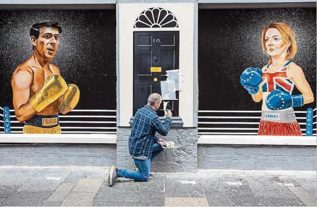  ?? Foto: AFP ?? Der Künstler Ciaran Gallagher vollendet sein Werk in Belfast: Die Tory-Kandidaten Liz Truss und Rishi Sunak warten auf das Finale am Montag.