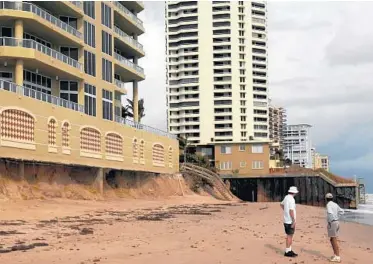  ?? MARK RANDALL/STAFF PHOTOGRAPH­ER ?? Beachgoers look at erosion that went all the way under the Ocean’s Edge condominiu­m on Singer Island.