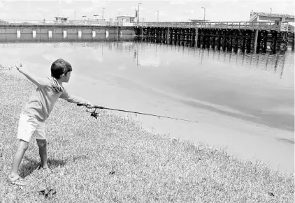  ?? PEDRO PORTAL/TNS ?? Zayden Drake Taylor fishes at W.P. Franklin Lock and Dam park in LaBelle, where an algae bloom could be seen along the canal on June 27.