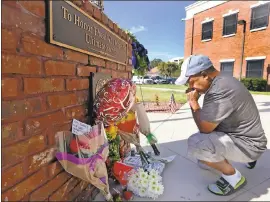  ?? RED HUBER, THE ORLANDO SENTINAL VIA AP ?? After placing flowers at a makeshift memorial, Miguel Velez says a prayer for Sgt. Sam Howard, the officer who died from his wounds in Kissimmee, Fla., on Saturday. His colleague, Officer Matthew Baxter, died Friday night after the attack in a...