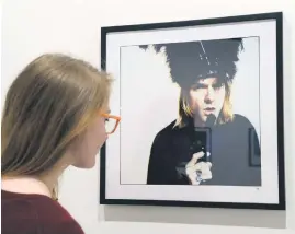  ?? The Last Shooting, ?? ICONIC. A woman looks at a photo of singer Kurt Cobain, posing with a handgun, as part of the 2014 exhibition, in Paris.