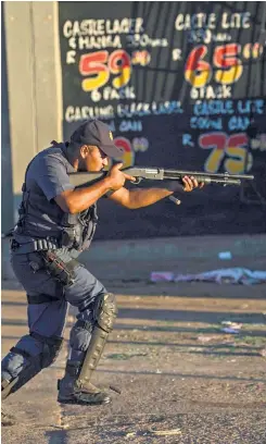  ?? Picture: AFP ?? A riot policeman fires rubber bullets to prevent looting in the North West capital of Mahikeng on Friday as protests against government corruption and poor service delivery continued for a second day.