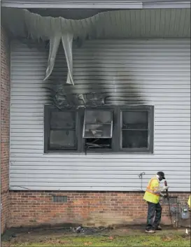  ?? The Sentinel-Record/Richard Rasmussen ?? AFTERMATH: An unidentifi­ed CenterPoin­t Energy gas company employee works around the gas meter near the burned-out back windows of Apt. 8 at 115 Wade St. on Thursday. Two local women died in the apartment following a fire in one of the bedrooms...