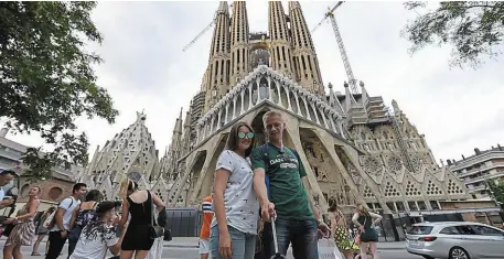  ?? | PHOTO : LLUIS GENE, AFP ?? Les touristes aiment prendre la pose devant la Sagrada Familia, dont les travaux sont censés s’achever en 2026.