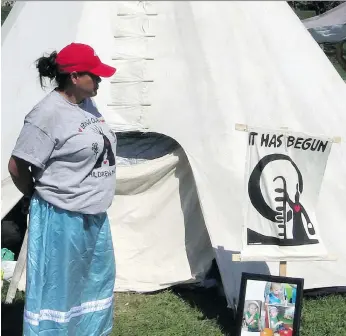  ?? POSTMEDIA ?? Darla Fourstar, who was in the foster-care system as a child, stands by the teepee at the Healing Camp for Justice in Victoria Park in support of her friend Chris Martell.