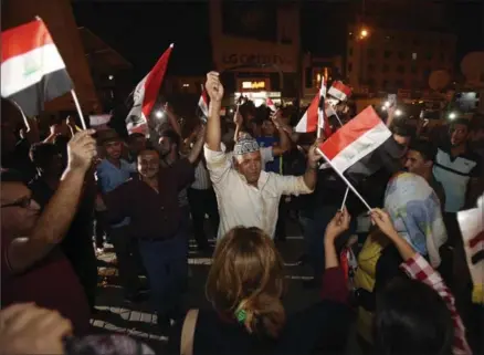  ?? KARIM KADIM, THE ASSOCIATED PRESS ?? Iraqis celebrate while holding national flags in Tahrir Square in Baghdad, Iraq, Monday. Iraqi Prime Minister Haider al-Abadi declared victory against the Islamic State group in Mosul Monday evening, after nearly nine months of largely gruelling urban...
