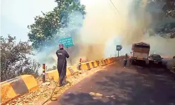  ?? ANI ?? Red alert: A firefighte­r works on dousing a fire in the mountains near Nainital. As many as 23 new forest fires were reported in Uttarakhan­d on Saturday.