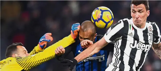  ?? — AFP ?? Safety first: Inter Milan goalkeeper Samir Handanovic, Inter defender Joao Filho and Juventus’ Mario Mandzukic (right) going for the ball in the Serie A match on Saturday.