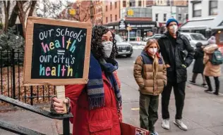  ?? Brittainy Newman / Associated Press ?? A teacher holds a sign Tuesday in solidarity with other educators speaking out on COVID testing for students in New York. Schools across the U.S. face the return of remote learning.