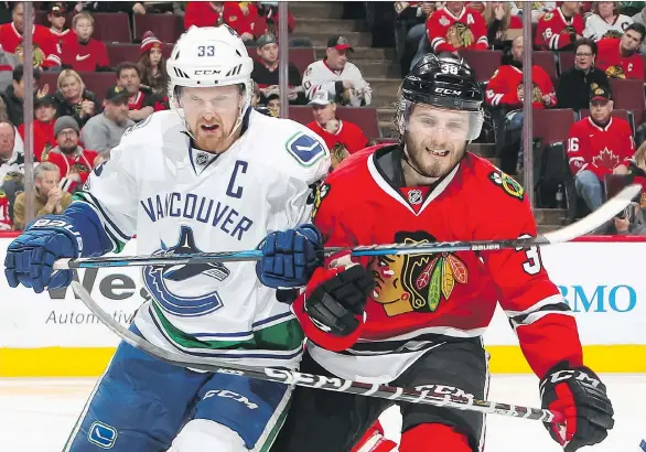  ?? CHASE AGNELLO-DEAN/NHLI VIA GETTY IMAGES ?? Vancouver Canucks centre Henrik Sedin jostles Chicago Blackhawks left wing Ryan Hartman during the second period on Sunday in Chicago.