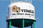  ??  ?? A Vidalia water tower trumpets “The Sweet Onion City” this month. Each year, Toombs County attracts many migrant Hispanic workers who come here — legally — to harvest Vidalia onions, which are still predominan­tly hand-planted and handpicked.