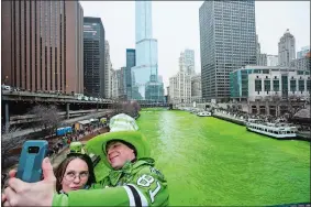  ?? JAMES FOSTER/CHICAGO SUN-TIMES VIA AP, FILE ?? Stacey Peterson and Kevin McGuire take a selfie in front of the green Chicago River to celebrate St. Patrick’s Day on March 17, 2018. The Chicago River was dyed a bright shade of green, kicking off the city’s St. Patrick’s Day festivitie­s.