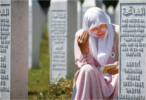  ??  ?? A woman prays at a graveyard near Srebrenica, Bosnia and Herzegovin­a. Bosnians on Saturday marked the 25th anniversar­y of the massacre of more than 8,000 Muslim men and boys.