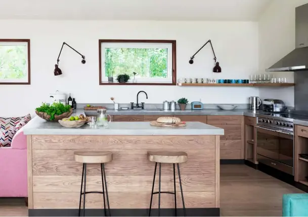  ??  ?? KITCHEN
Minimal cabinetry was crafted from wire-brushed oak with integrated handles. The steel and wooden bar stools are from Cox & Cox, while the wall-mounted Anglepoise lamps are from Twentytwen­tyone
DINING AREA Taking his inspiratio­n from legendary furniture designer Pierre Jeanneret, interior designer Willie Nickerson created the rustic-style dining table. Classic wooden chairs from 1st
Dibs complete the look