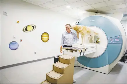  ?? PHOTOS BY DUSTIN CHAMBERS / THE NEW YORK TIMES ?? Dr. Gregory Berns, a neuroscien­tist at Emory University, interacts with Zen, a retriever mix, near a magnetic resonance imaging machine in Atlanta. Berns scans the brains of dogs for glimpses at their inner lives. One conclusion: Fido does love you.