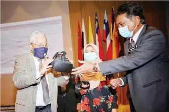  ?? — Photo by Chimon Upon ?? Manyin (left) about to put on a virtual reality headset during the launching of the book yesterday. At right is Batu Lintang Teacher Education Institute director Jamiran Salam.