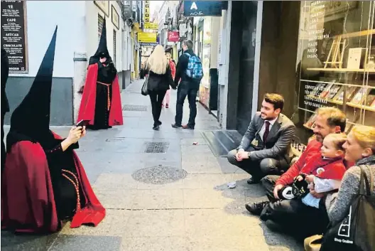  ?? RICART. ?? Un cofrade de la Semana Santa andaluza fotografía a un grupo de personas en una de las calles del centro de Sevilla