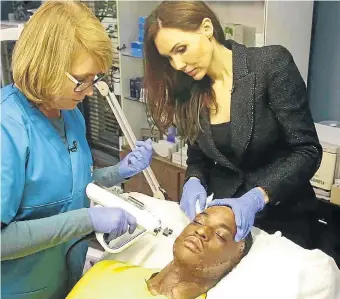  ?? Picture: Supplied ?? Dr Cathy Davies, right, and an assistant operate on Qaphela Gobodo, who was badly scarred after being doused with paraffin and set alight by envious schoolmate­s.