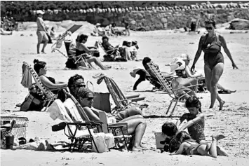  ?? CHARLES KRUPA/AP ?? Beachgoers relax on the shore Friday at Good Harbor Beach in Gloucester, Massachuse­tts.