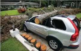  ?? The Associated Press ?? The remainder of the trunk of an oak tree brought down by Hurricane Irma remains on a crushed vehicle in Maitland, Fla.
