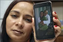  ?? CHRIS O’MEARA — THE ASSOCIATED PRESS ?? Yarelis Gutierrez Barrios holds up a cell phone photo of herself with her partner Roylan Hernandez Diaz, a Cuban asylum seeker who hanged himself in a Louisiana prison.