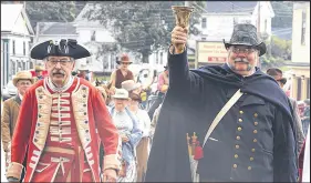  ??  ?? Annapolis Royal’s town crier Peter Crofton Davies, left, looks on as his Sackville colleague Greg Fenwick rings his bell, while marching in the costume parade through Maitland.