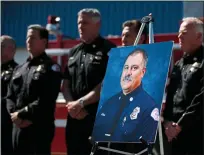  ??  ?? “Hero”: fellow firefighte­rs stand next to a photo of Dave Rosa, who was shot dead while responding to reports of an explosion at a retirement home in California