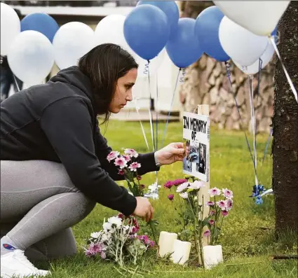  ?? Carol Kaliff / For Hearst Connecticu­t Media ?? Kassidy Lopez, above, a close friend of Brandon Forlastro, places flowers near his photograph before a candle-lighting vigil Monday evening near 243 Danbury Road in New Milford. The vigil is to remember Brandon, who died in a motorcycle accident Sunday.